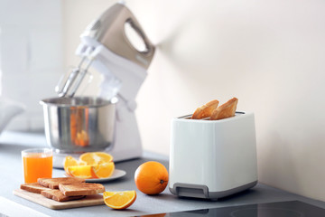 Toaster with mixer and oranges on a light kitchen table