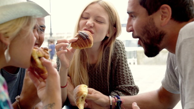 Multiethnic friends have breakfast eating jam stuffed brioches