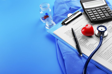 Medical stethoscope, clipboard, coat and calculator on blue background