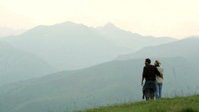 Couple on mountain is whatching panorama at sunset