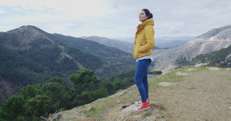 Obraz premium Woman in yellow coat near mountain valley