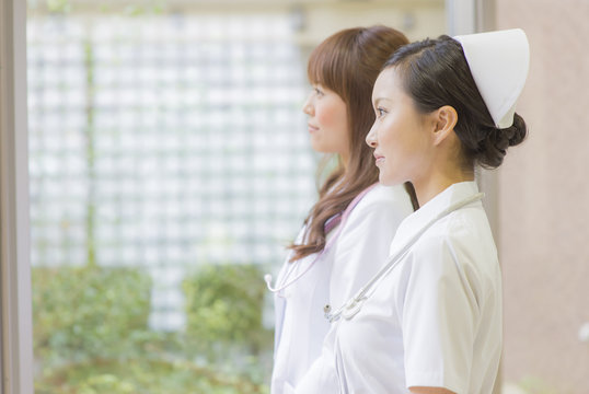 病院内から外を見る女性医師と女性看護師