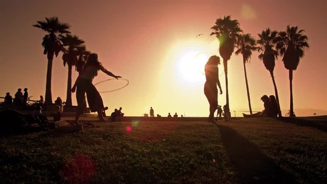 Lens flare shot of people strolling near Venice Beach, California filmed in slow motion