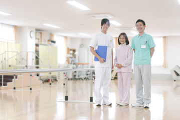リハビリ室に立つ患者と男性理学療法士と男性看護師