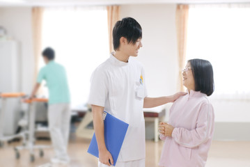 女性患者の肩に手を置く男性看護師