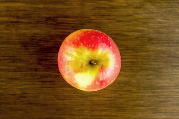 Over head of red and yellow apple against dark oak wood
