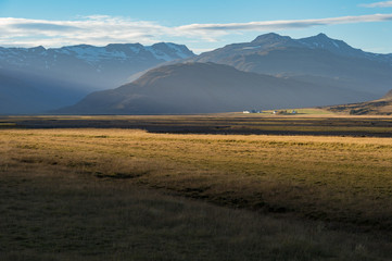 Beautiful scene when light touch yellow field and small farm with great mountain range background in Autumn season Iceland