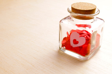 Hearts in a glass jar on wooden surface