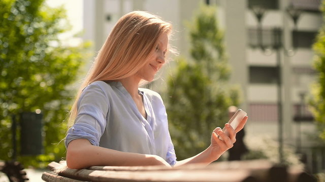 Girl on the smartphone sit on a bech