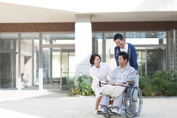 車椅子に座った笑顔の男性患者と男性医療スタッフと女性看護師