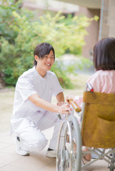 車椅子の女性患者に微笑みかける男性看護師