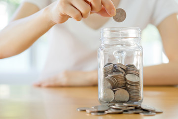 Woman hands with coins in glass jar, close up