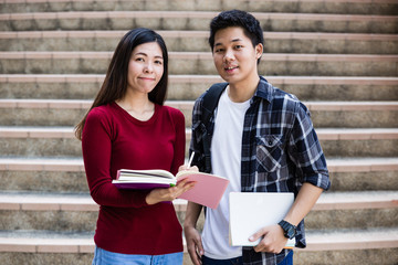 Two students studying with computer notebook outdoors