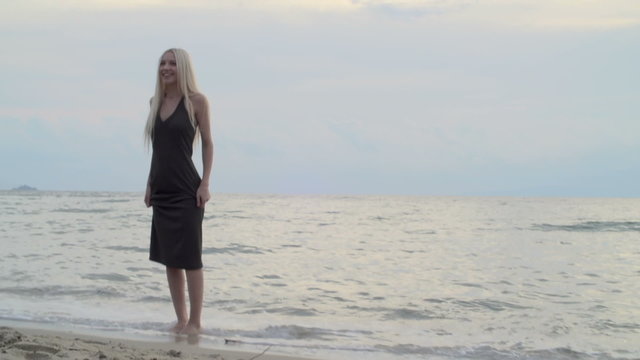 Woman wet feets on beach at sunset