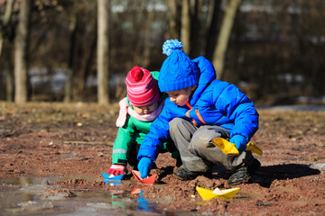 little boy and toddler girl playing with water in spring