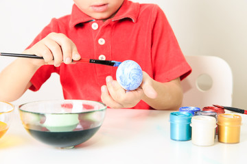 little boy painting eggs for easter