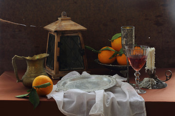 Wine in a transparent glass, oranges and an old lantern