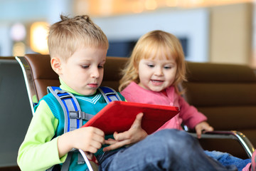 Obraz premium kids looking at touch pad while waiting in the airport