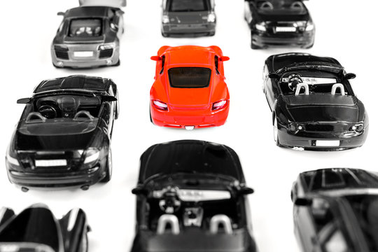 Red Toy Car Standing Out From Crowd Of Plenty Identical Black Car