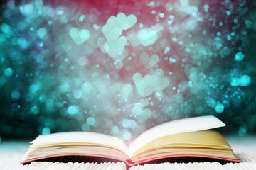 Open book over heart shaped bokeh