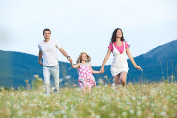 Happy family are resting in a chamomile field
