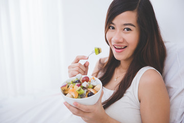 Beautiful pregnant woman with a bowl of fruit, white background