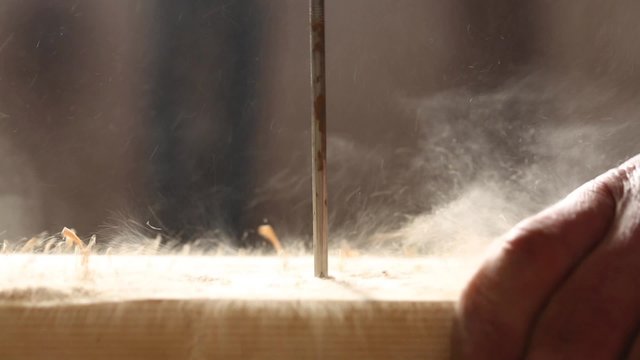 Joiner drive a nail into a board. Close-up, the dust flying from the wood.