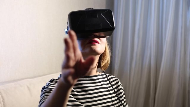 Close-up young beautiful girl getting experience using VR-headset glasses of virtual reality at home