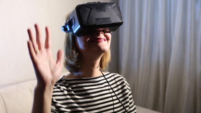 Close-up happy smiling young beautiful girl getting experience using VR-headset glasses of virtual reality at home