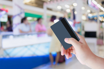 hand hold credit card with blurred people in shopping center