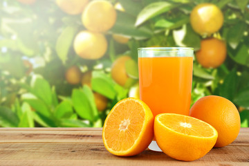 Orange juice and oranges on wooden table.