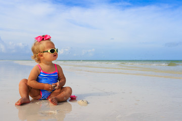 cute little girl playing with shells on beach