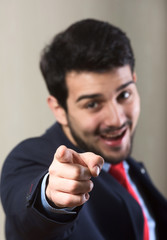 Portrait of a cheerful man pointing at the camera (with focus to his hand)