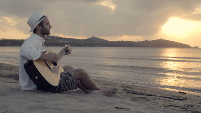 Man play guitar on beach at sunset  slow motion