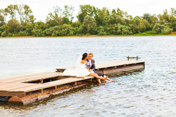 Beautiful bride with groom by a lake. Kiss and hug each other