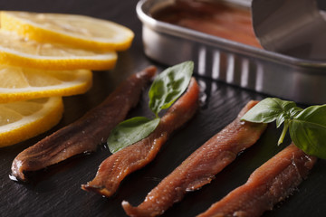 Anchovy fillets and lemon macro on a slate board. Horizontal
