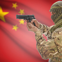 Male with gun in hands and national flag on background - China