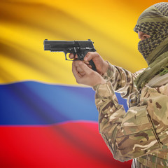 Male with gun in hands and national flag on background - Colombia