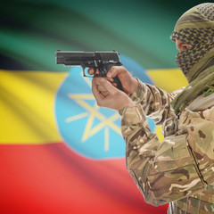 Male with gun in hands and national flag on background - Ethiopia