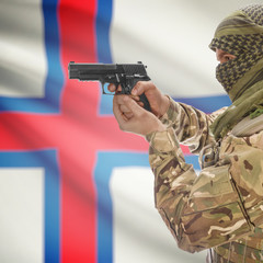 Fototapeta premium Male with gun in hands and national flag on background - Faroe Islands