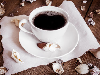 Cup of coffee on wooden background, decorated dried aromatic parts of plants