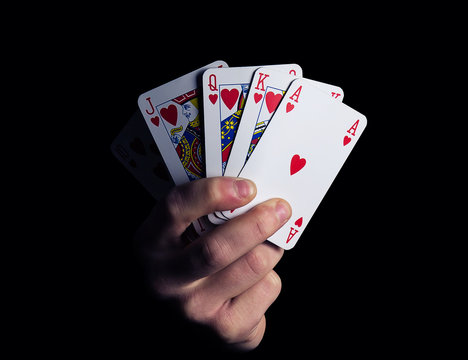 man hand shows royal flush playing card combination close-up on a black background