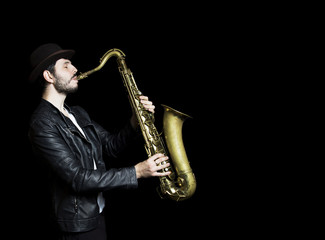 Fototapeta premium A saxophone player in a hat. dark background. Saxophonist jazz