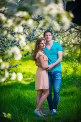 Naklejka na ściany i meble Young beautiful couple in love among apple trees
