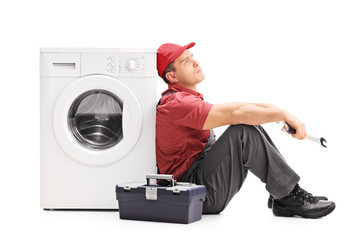 Plumber sitting by a washing machine and thinking