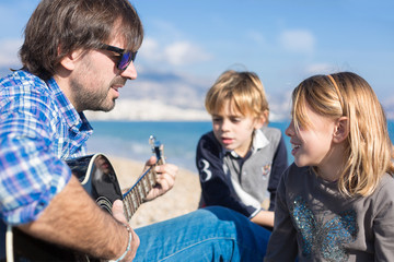 Children and father singing song on beach