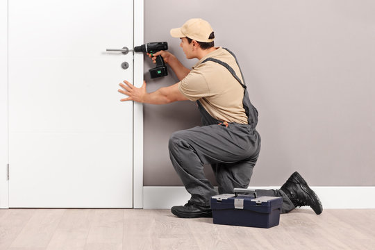 Young Locksmith Installing A Lock On A Door