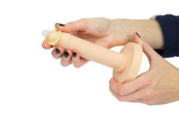 Female hands unrolling condom on plastic penis model