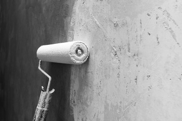 Paint roller applying paint on white wall, home improvements