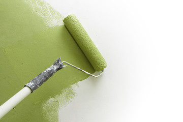 Paint roller applying paint on white wall, home improvements